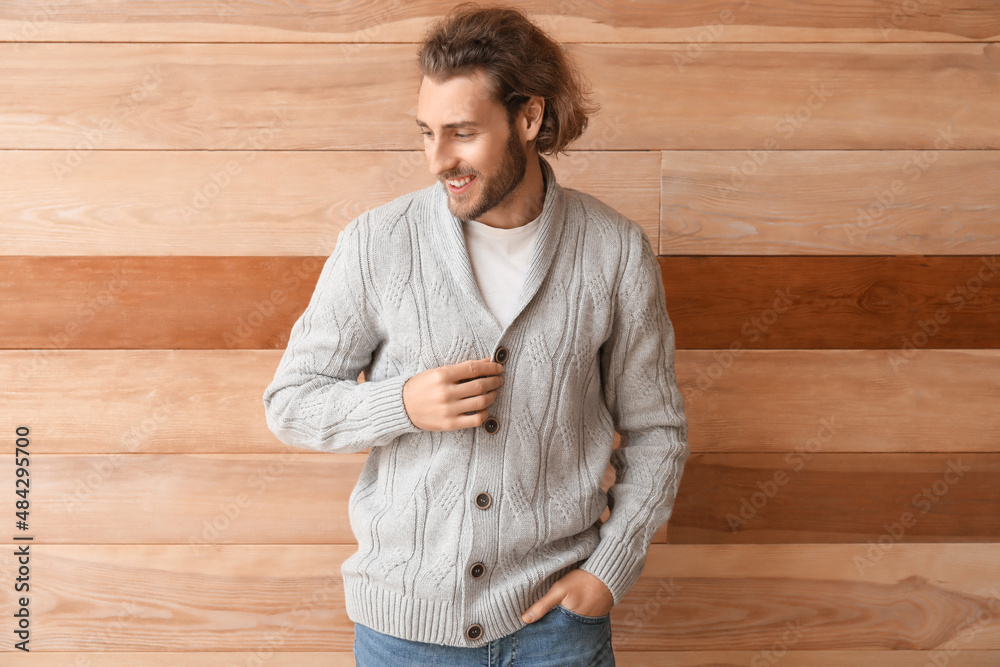 Handsome young man in knitted sweater on wooden background