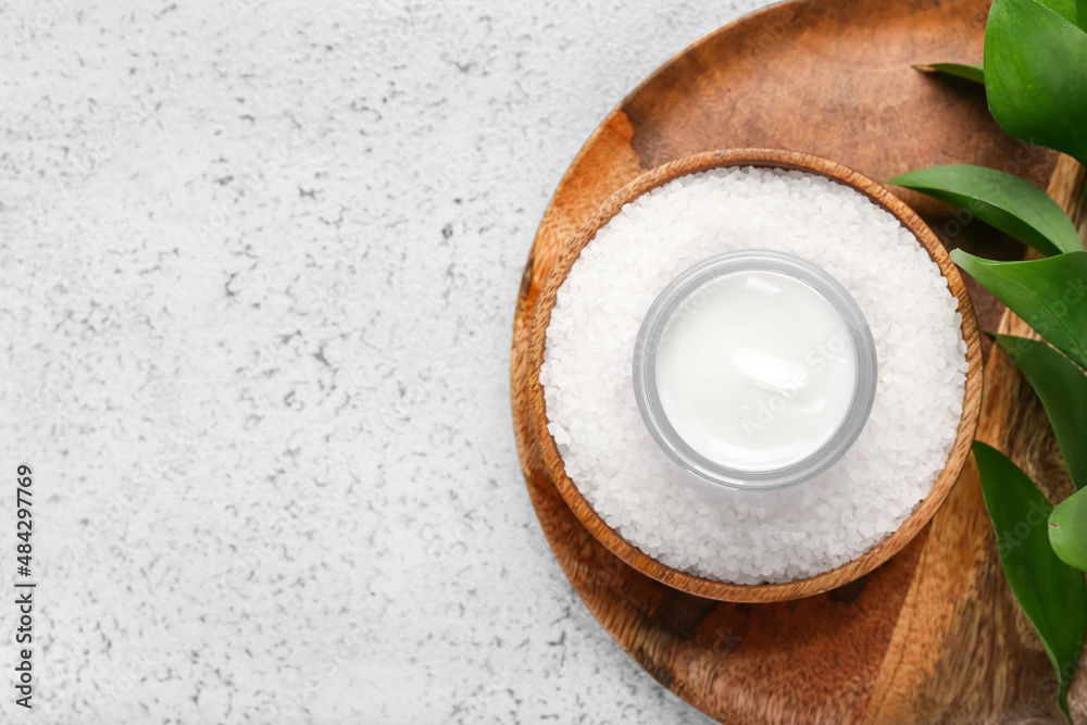 Jar with natural cosmetic cream and sea salt on light background