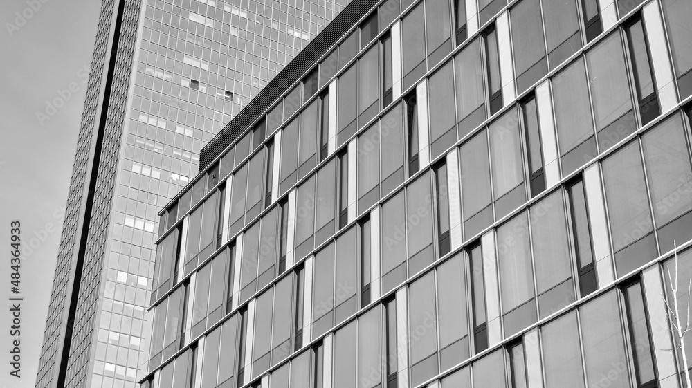 Modern glass and aluminum wall of office building outdoor with bright sun rays falling. Black and wh