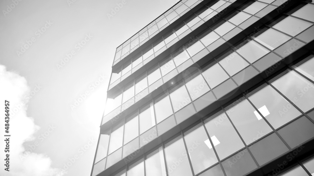 Modern glass and aluminum wall of office building outdoor with bright sun rays falling. Black and wh