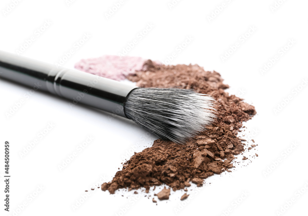 Makeup brush and loose eye shadow on white background