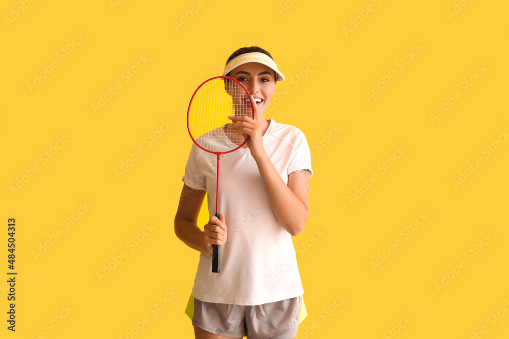 Happy female badminton player on yellow background