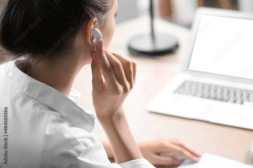 Pretty young woman listening to music while working in office