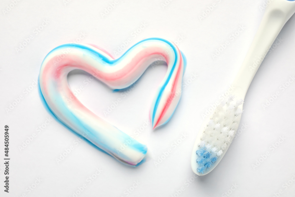 Heart made of toothpaste and brush on light background, closeup