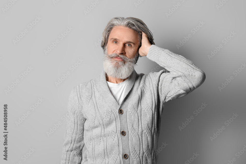 Handsome senior man in knitted sweater on grey background