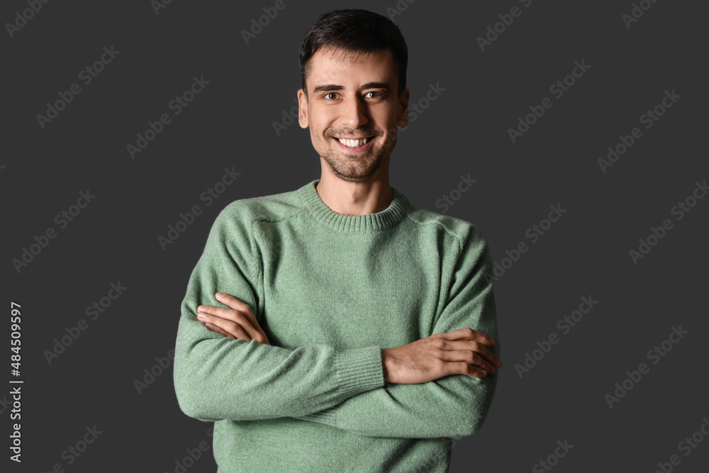 Handsome young man in knitted sweater on dark background