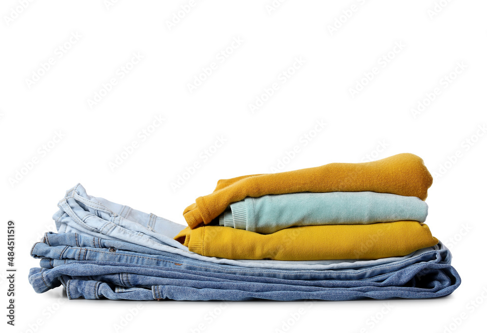 Stack of female jeans and sweaters on white background