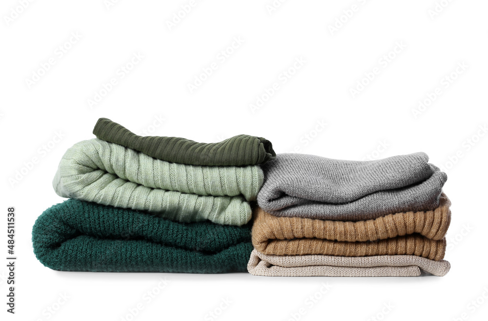 Stacks of different female sweaters on white background