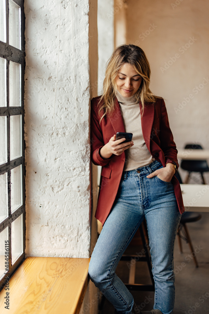 Smiling caucasian modern woman, browsing the internet on her phone.