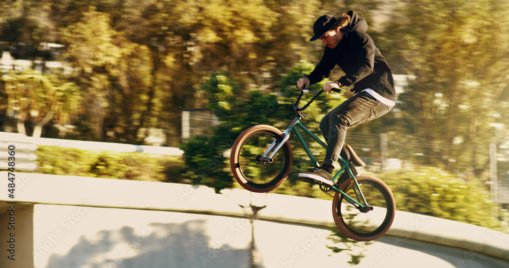 一些严肃的空气。一名年轻的BMX男性骑手在城市里玩把戏的全长镜头。