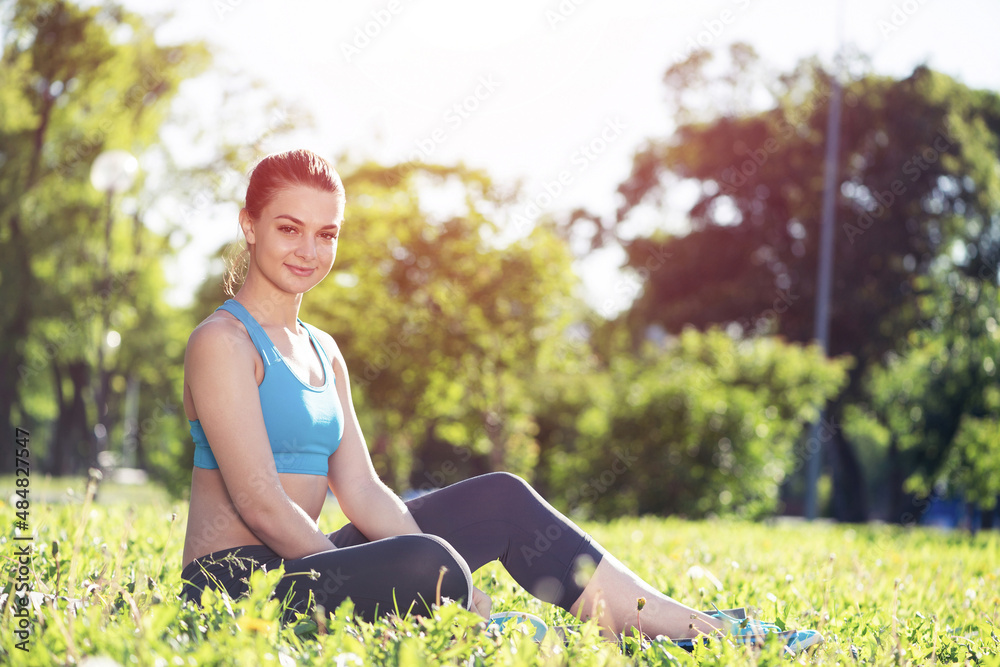 Beautiful smiling girl in sportswear relax in park