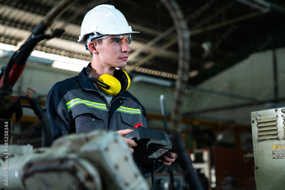 Young factory worker working with adept robotic arm in a workshop . Industry robot programming softw