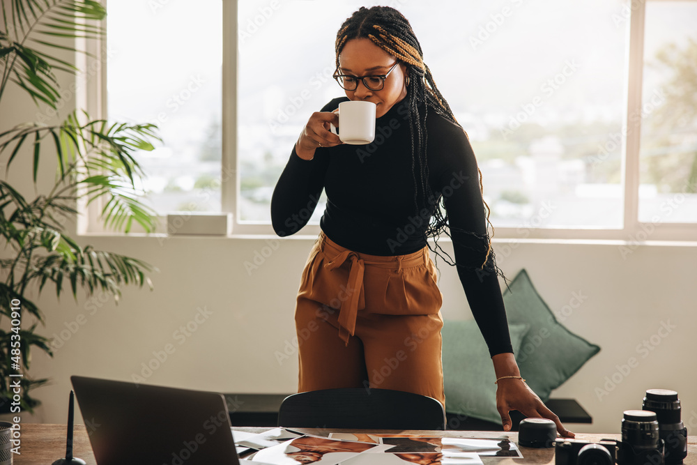 Self-employed young woman having coffee in her office