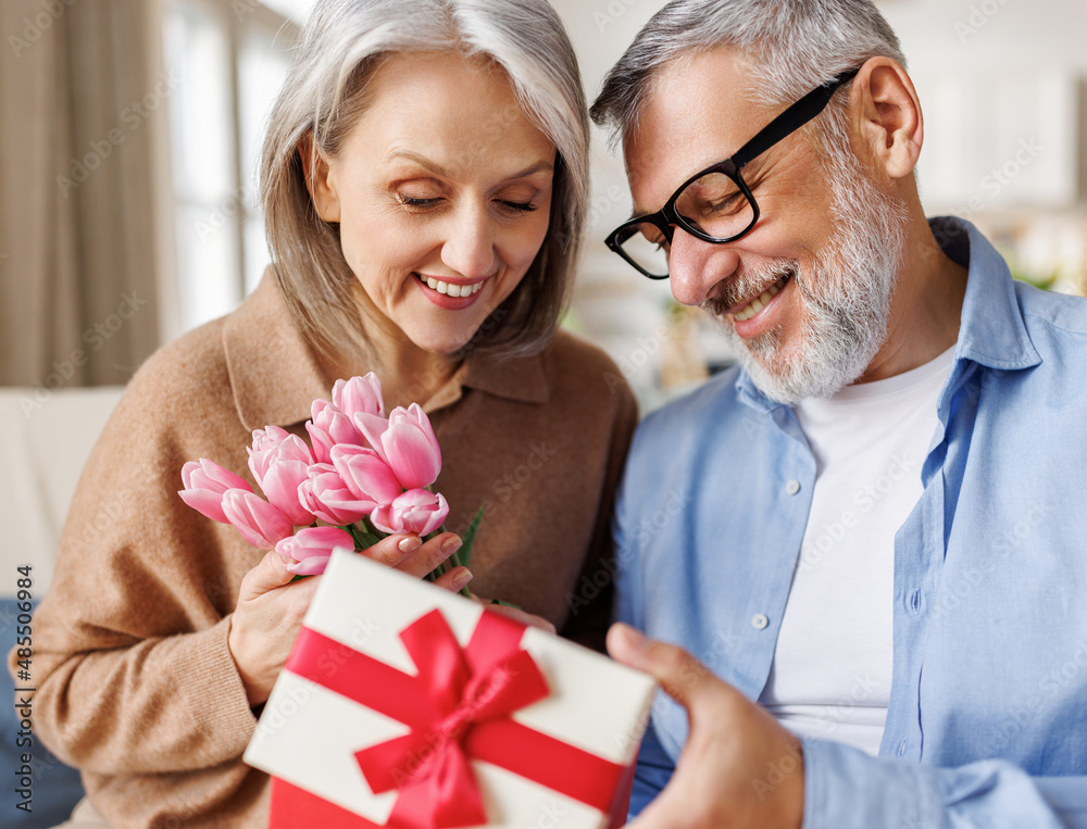 Romantic senior man congratulating happy wife on Valentines Day at home