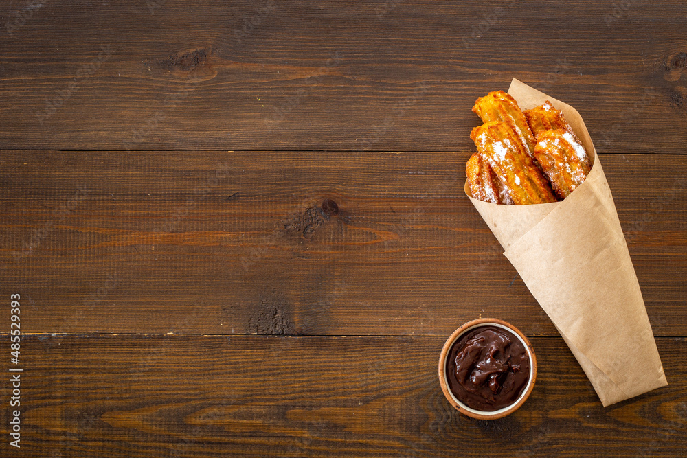 Street food dessert churros in paper bag with sugar