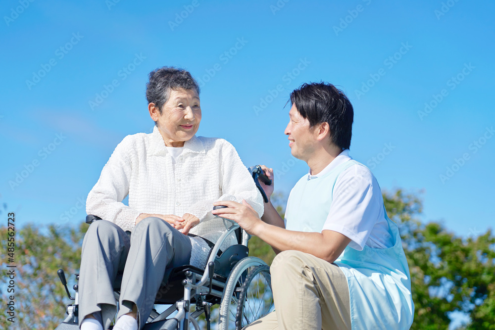 介護士と車椅子に乗る高齢者　屋外