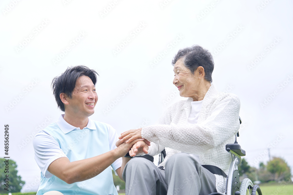 介護士と車椅子に乗る高齢者　屋外