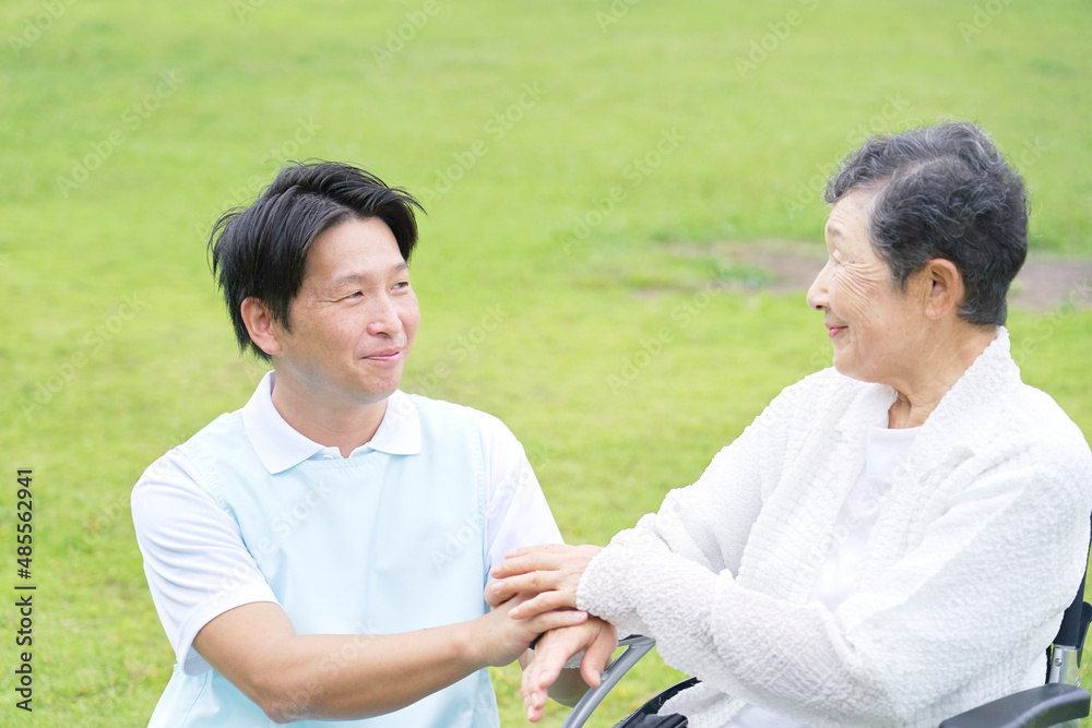 介護士と車椅子に乗る高齢者　屋外