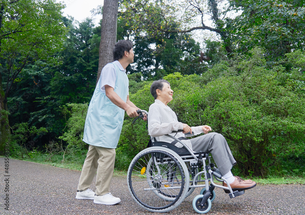 介護士と車椅子に乗る高齢者　屋外