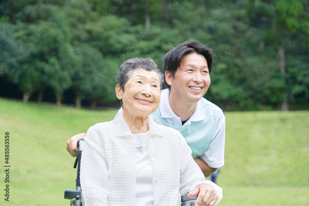 介護士と車椅子に乗る高齢者　屋外