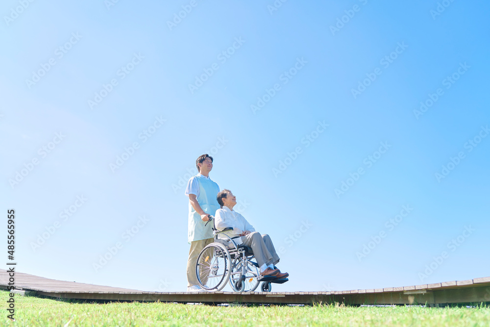 介護士と車椅子に乗る高齢者　屋外