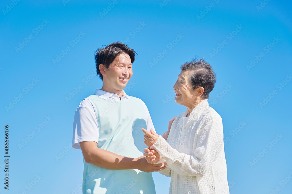 介護士と車椅子に乗る高齢者　屋外