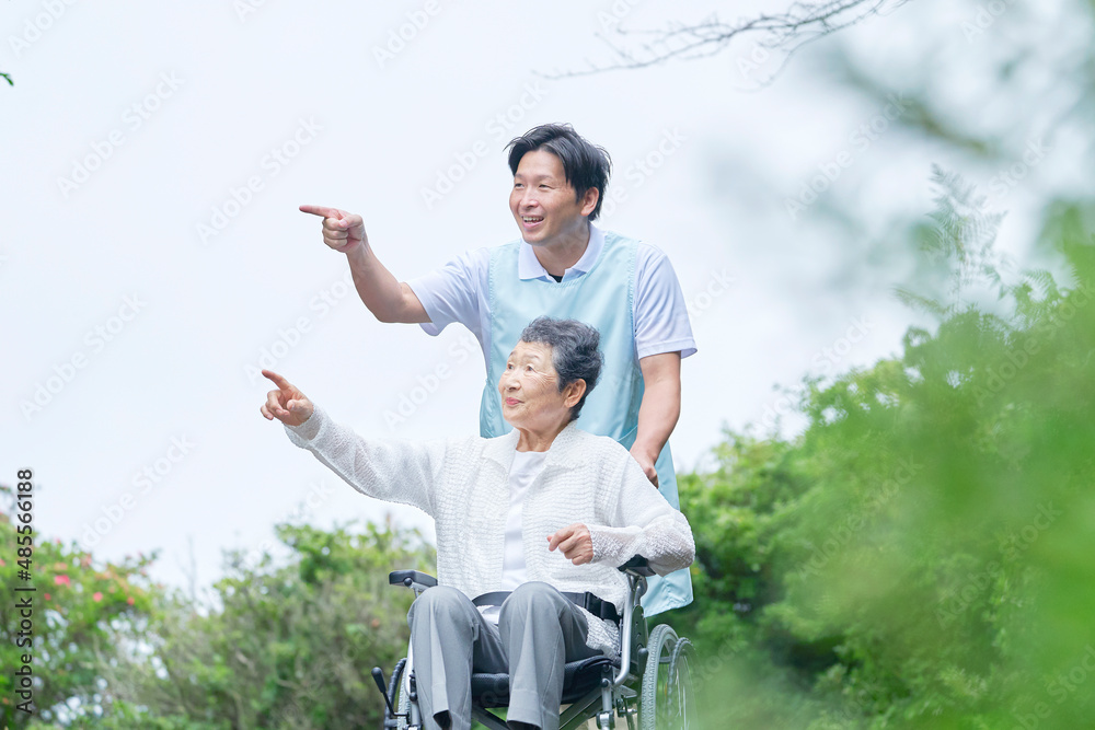 介護士と車椅子に乗る高齢者　屋外