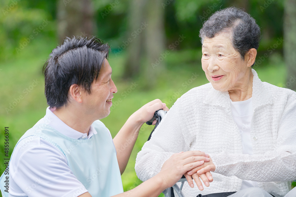 介護士と車椅子に乗る高齢者　屋外