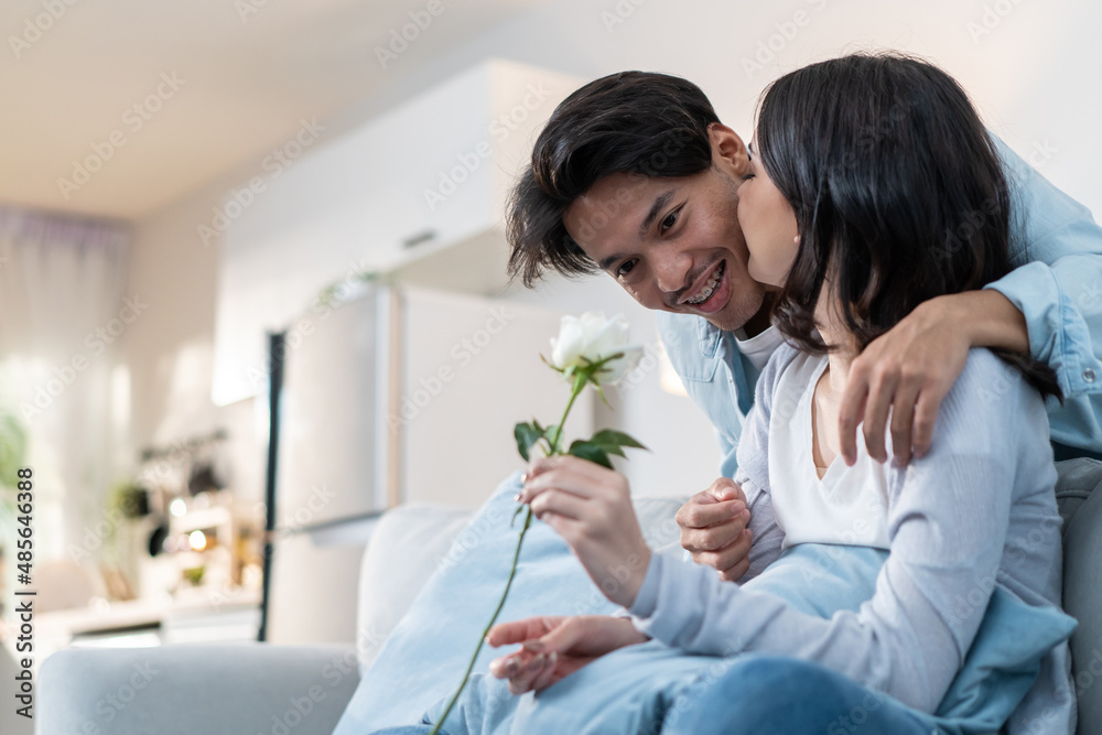 Asian young man surprise and give rose flower to beautiful girlfriend. 