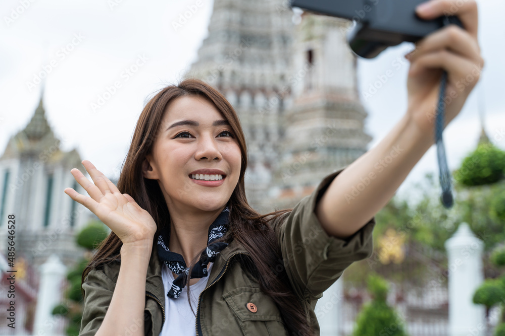 亚洲女背包客在城市里使用相机自拍和拍照。