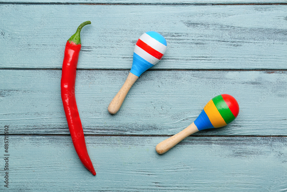 Hot chili pepper and Mexican maracas on blue wooden background