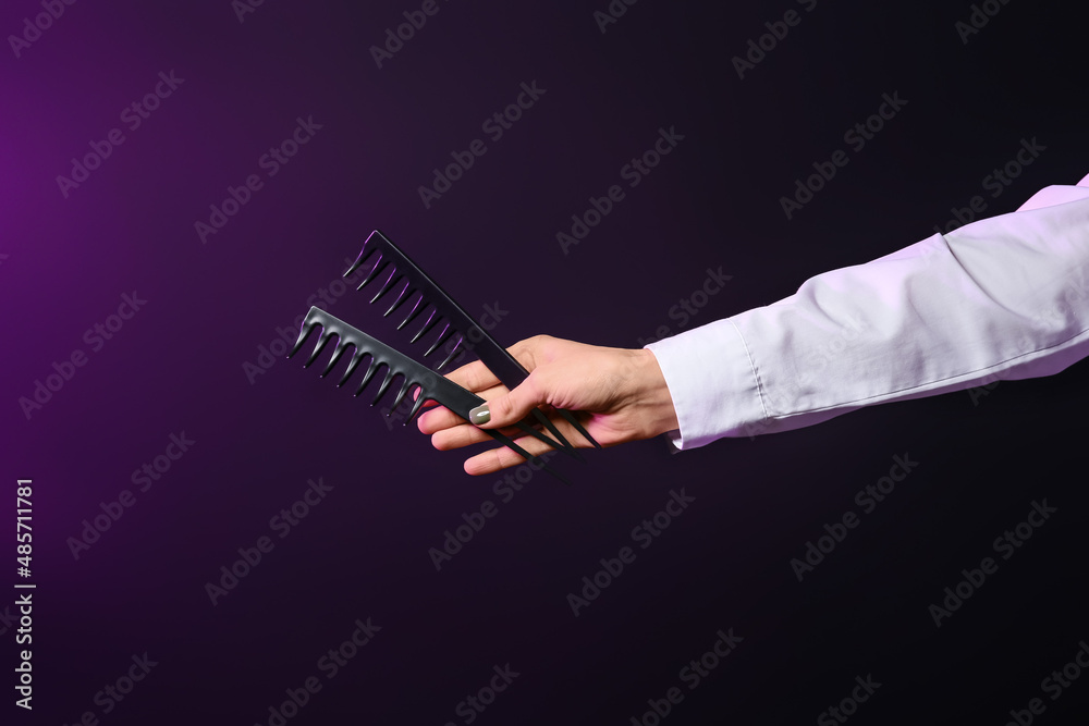 Female hand with hair combs on dark background