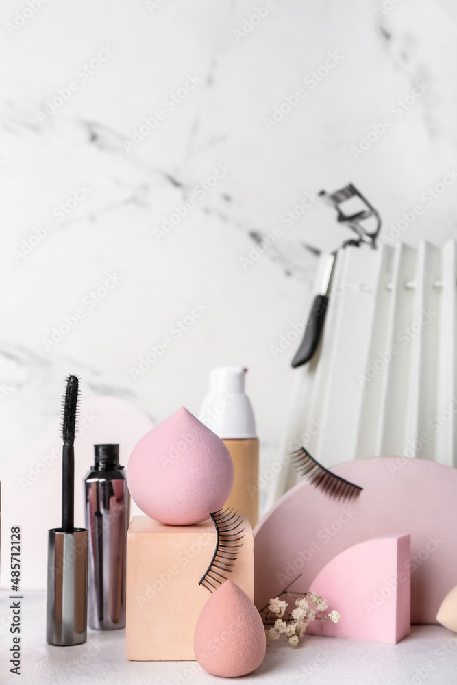 Composition with makeup sponges and cosmetics on light background