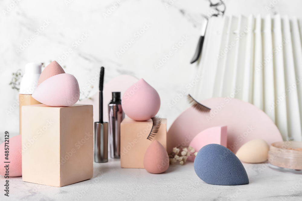 Composition with makeup sponges and cosmetics on light background