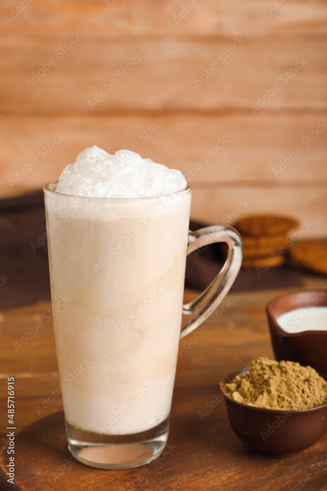 Glass of tasty iced hojicha latte on wooden table, closeup