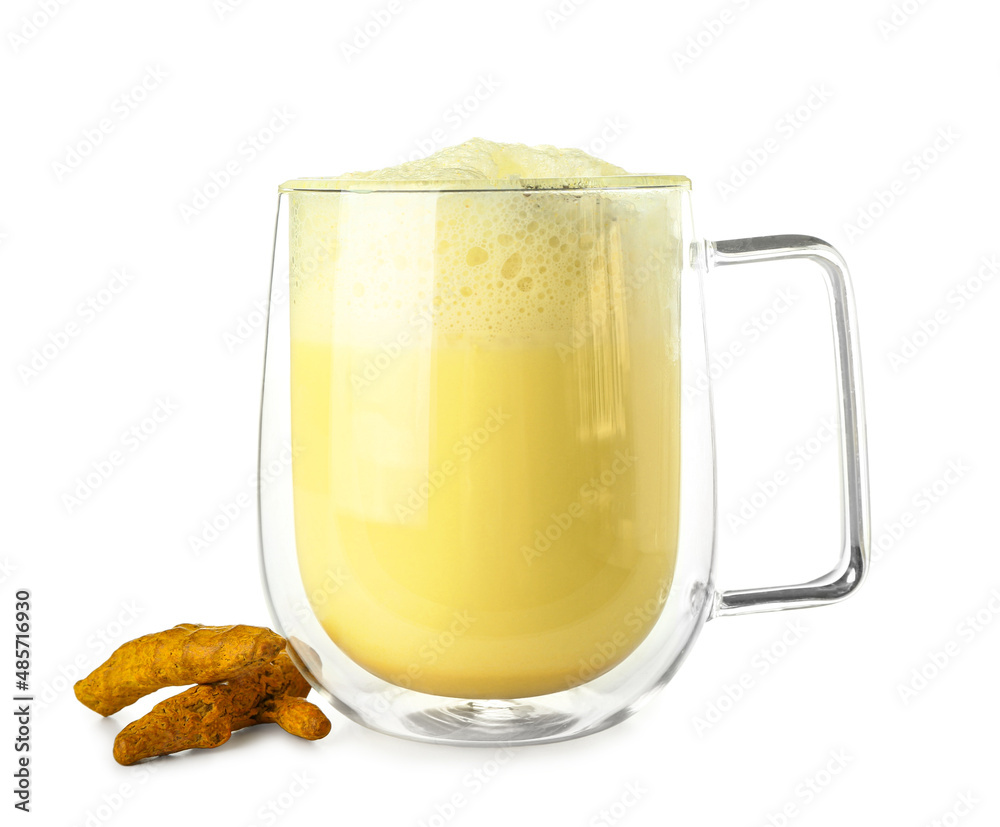 Glass cup of tasty turmeric latte and roots on white background