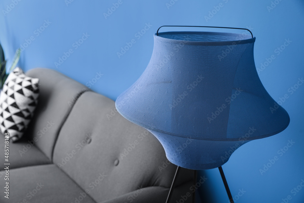 Stylish standard lamp and sofa near blue wall, closeup