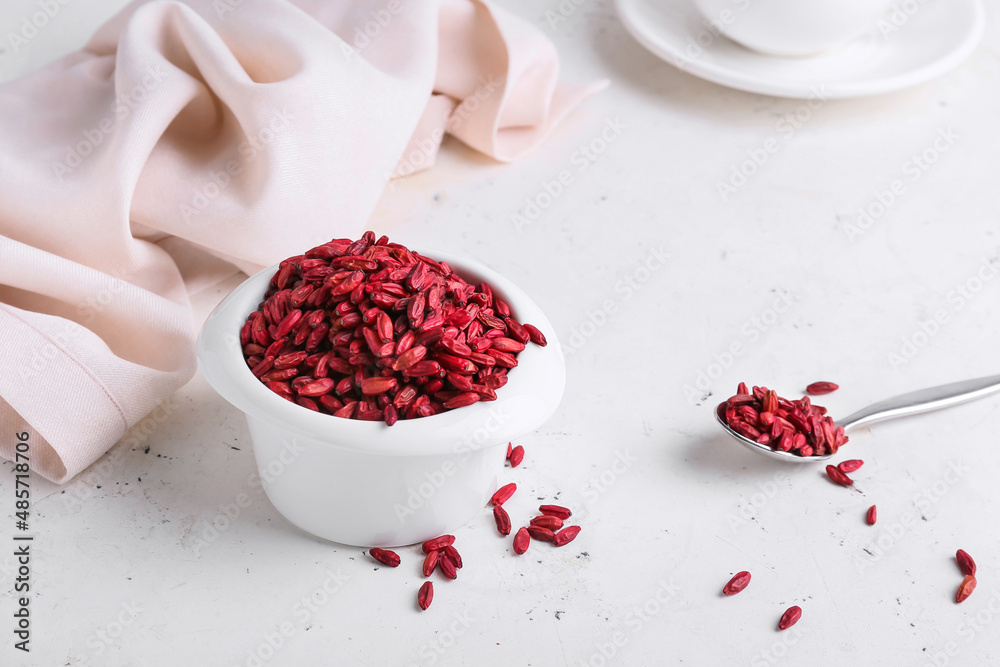 Bowl with dried barberries on light background