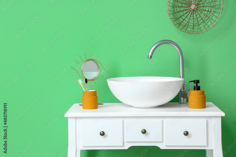 White table with sink, toothbrushes and soap near green wall