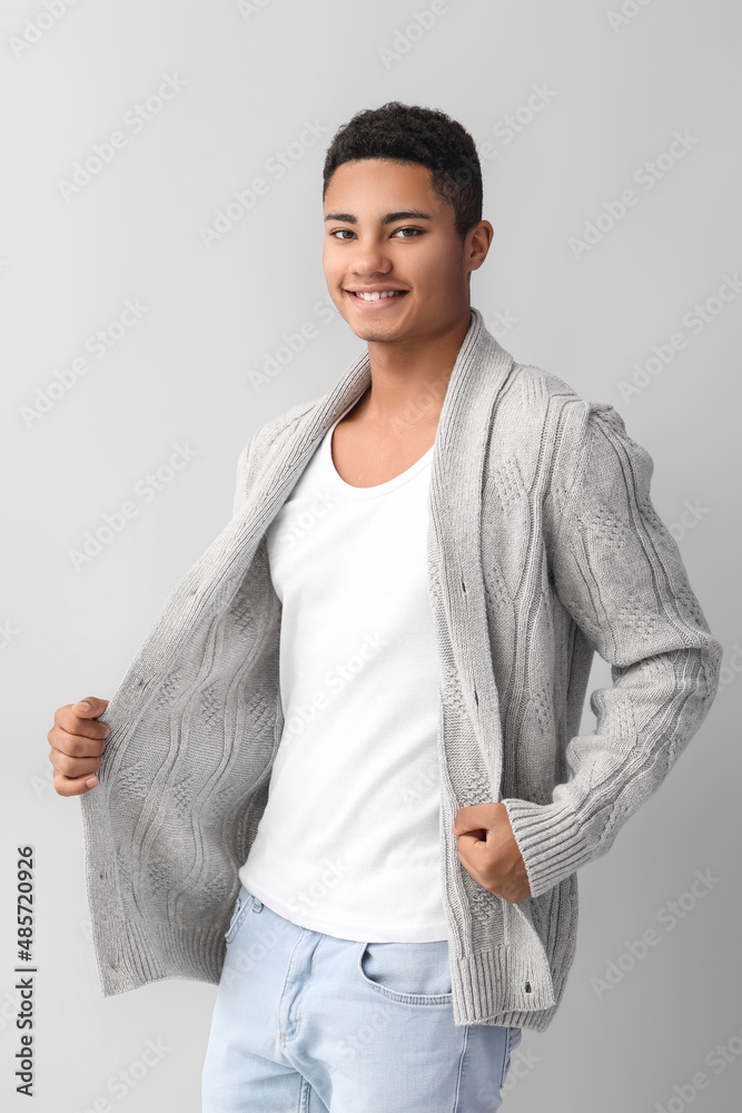 Handsome African-American guy in knitted sweater on light background