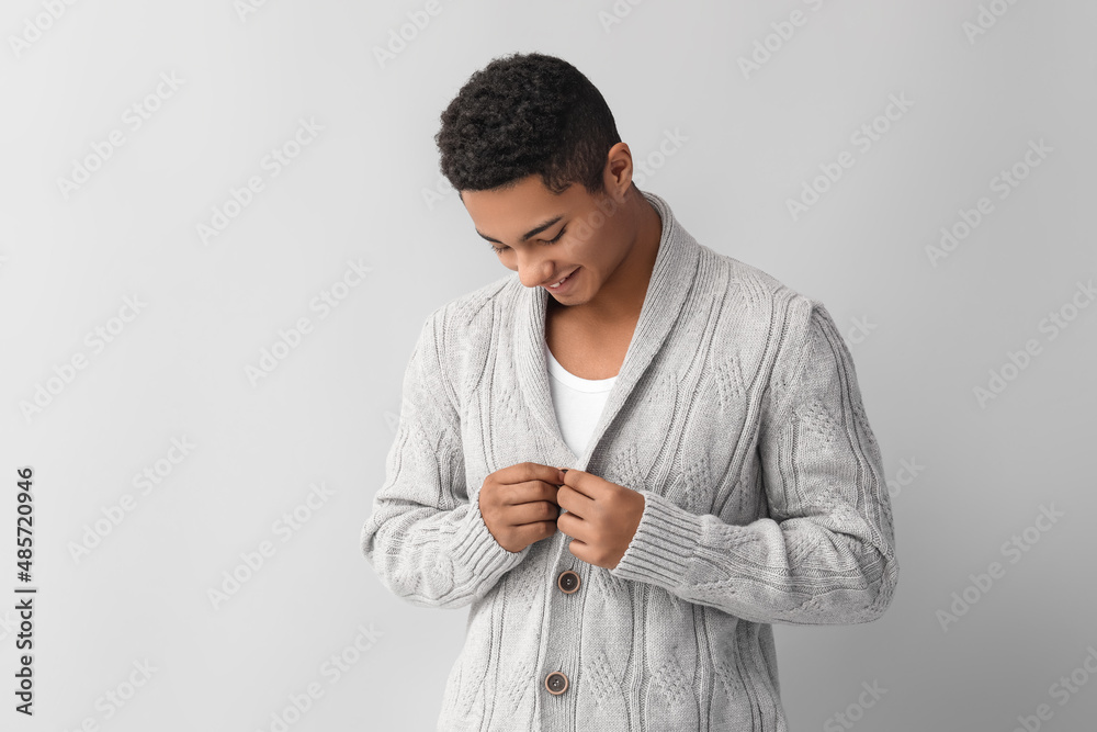 Handsome African-American guy in knitted sweater on light background