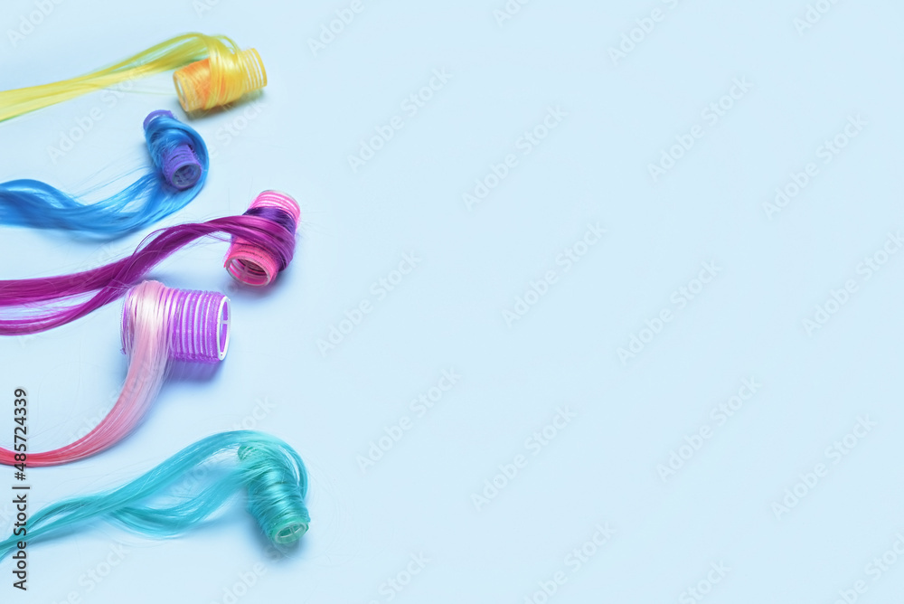 Different color hair strands with curlers on blue background