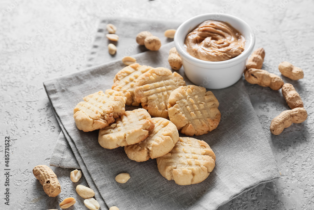 Tasty peanut cookies and butter on grey background