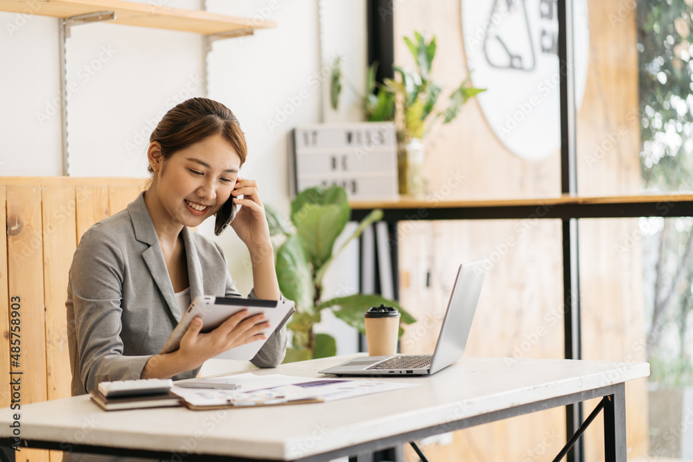 Young business woman on the phone at office. Business woman texting on the phone and working on lapt