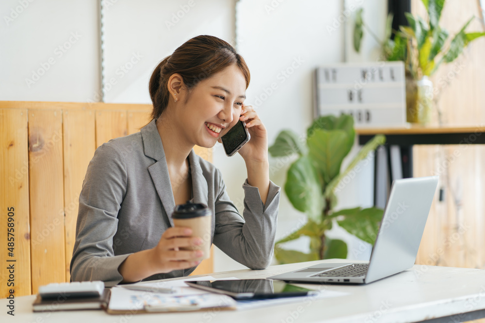 Young business woman on the phone at office. Business woman texting on the phone and working on lapt