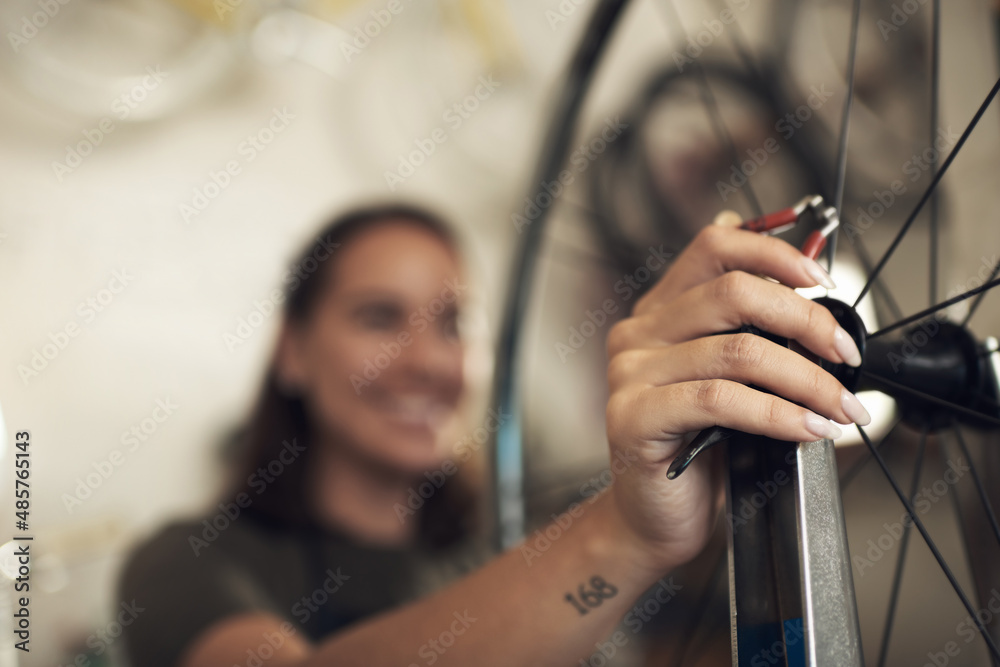 Say goodbye to bike problems. Shot of an unrecognizable woman standing alone in her shop and repairi