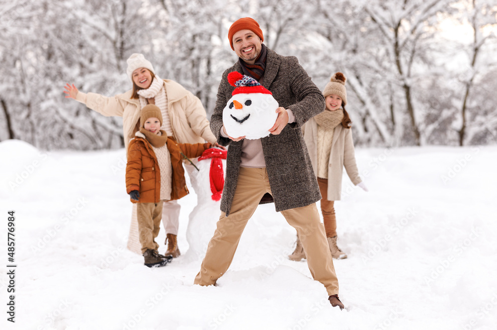 Cheerful family parents with kids in snowy winter park have fun and actively relax outdoors