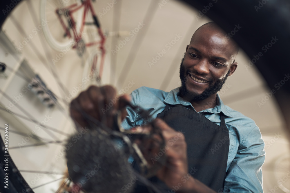 This bike really needed a new part. Low angle shot of a handsome young man standing alone in his sho