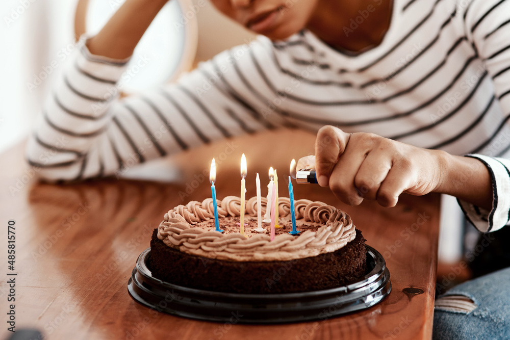 Birthdays in quarantine...not cool. Cropped shot of a woman lighting candles on a birthday cake at h