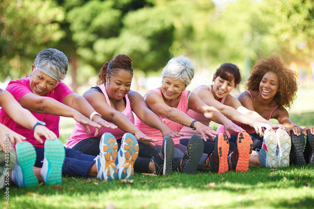 Having a laugh while limbering up. Shot of a group of people warming up outdoors.